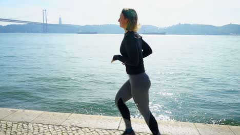 Sporty-young-woman-running-at-riverside